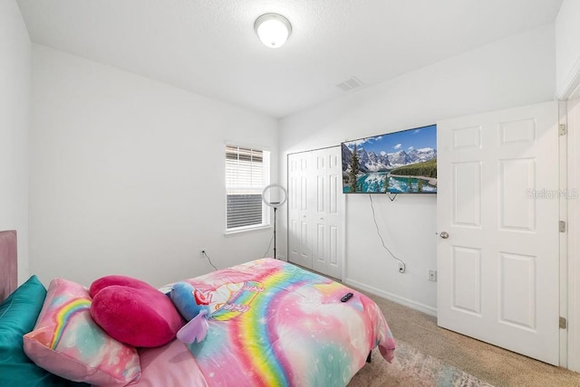 carpeted bedroom with baseboards, visible vents, and a closet