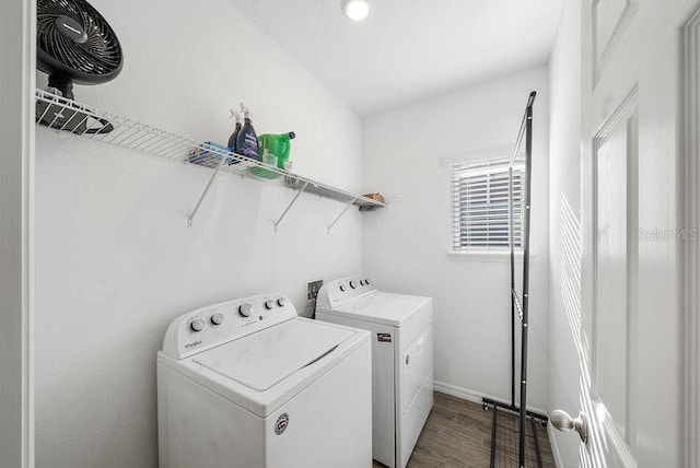 clothes washing area with laundry area, baseboards, washer and dryer, and wood finished floors