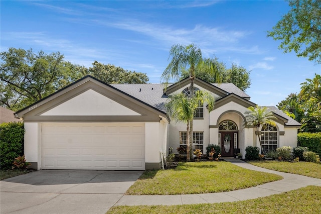 view of front of house featuring a front yard, an attached garage, driveway, and stucco siding