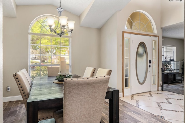 dining space featuring baseboards, wood finished floors, a chandelier, and vaulted ceiling