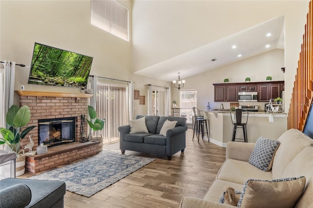 living area featuring light wood-type flooring, a notable chandelier, high vaulted ceiling, recessed lighting, and a fireplace