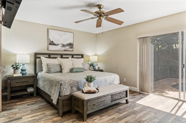 bedroom featuring access to exterior, a textured ceiling, baseboards, and wood finished floors