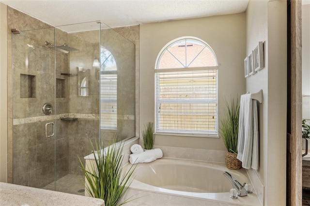 bathroom featuring a bath, a stall shower, and a textured ceiling