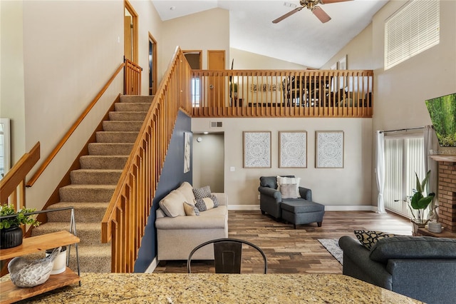 living area with wood finished floors, a ceiling fan, baseboards, and high vaulted ceiling