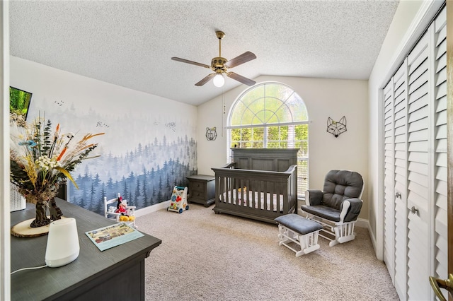 bedroom with lofted ceiling, a nursery area, carpet flooring, and a textured ceiling