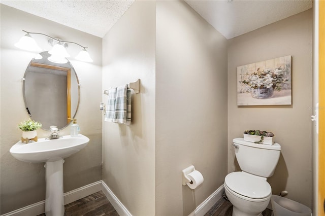 half bathroom with baseboards, toilet, and wood finished floors