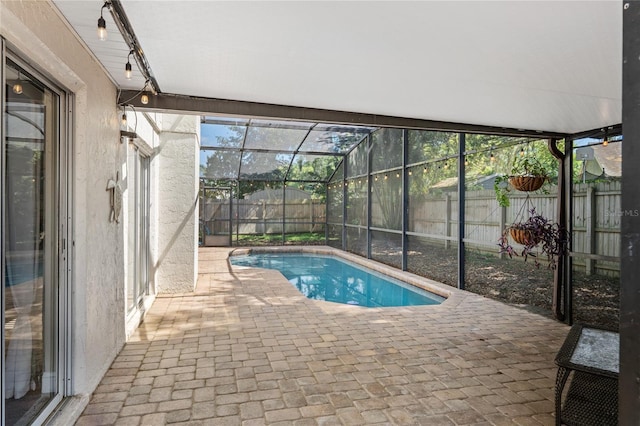 view of swimming pool with glass enclosure, a patio, a fenced in pool, and a fenced backyard