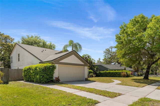 view of front of property featuring stucco siding, concrete driveway, a front yard, and fence