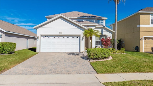 traditional-style house with an attached garage, a front lawn, decorative driveway, and stucco siding