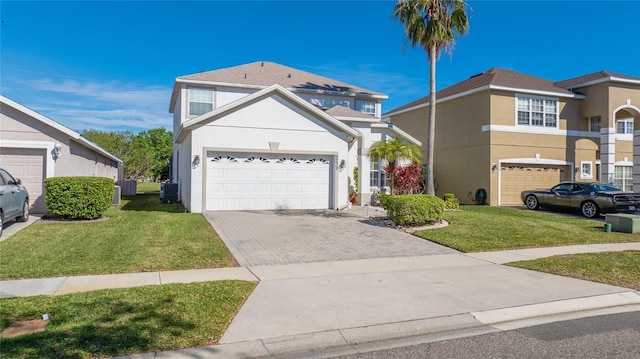 traditional home with central AC unit, a garage, decorative driveway, stucco siding, and a front yard