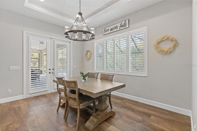 dining room with baseboards, ornamental molding, wood finished floors, an inviting chandelier, and a tray ceiling