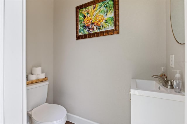 half bathroom featuring toilet, vanity, and baseboards