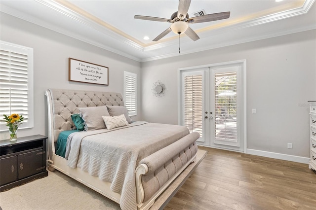 bedroom with a tray ceiling, french doors, light wood-style floors, ornamental molding, and access to outside