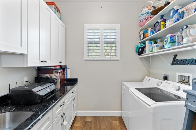 laundry area with cabinet space, washing machine and dryer, a sink, wood finished floors, and baseboards