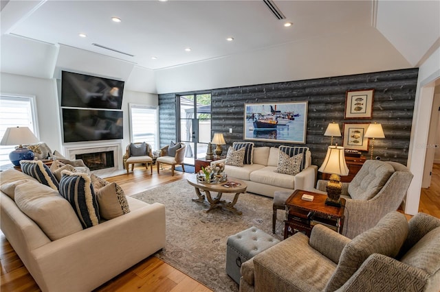 living area with visible vents, recessed lighting, a fireplace, wood finished floors, and rustic walls