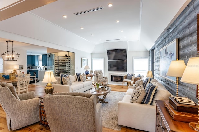 living room with a fireplace, lofted ceiling, wood finished floors, and visible vents