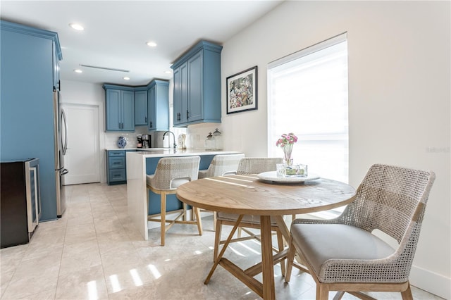 kitchen with backsplash, blue cabinetry, light countertops, a peninsula, and a kitchen breakfast bar