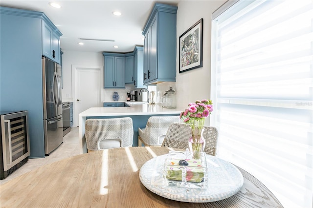 kitchen featuring wine cooler, stainless steel fridge, a peninsula, and blue cabinets