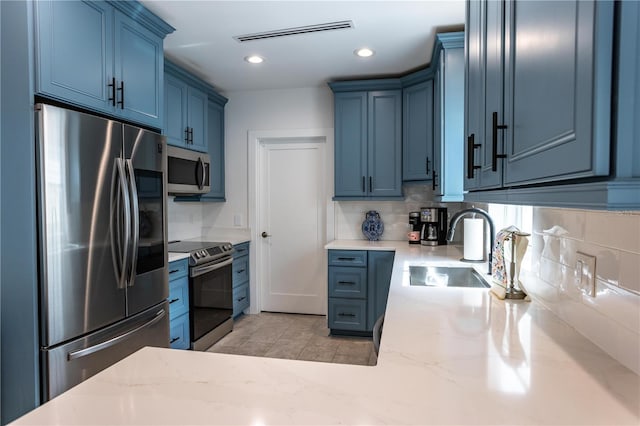 kitchen featuring blue cabinets, visible vents, a sink, appliances with stainless steel finishes, and decorative backsplash