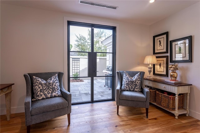 living area with light wood-style flooring, baseboards, visible vents, and french doors