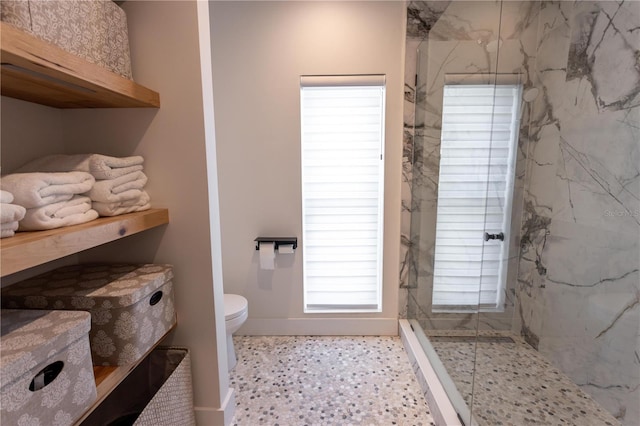 bathroom featuring a marble finish shower and toilet