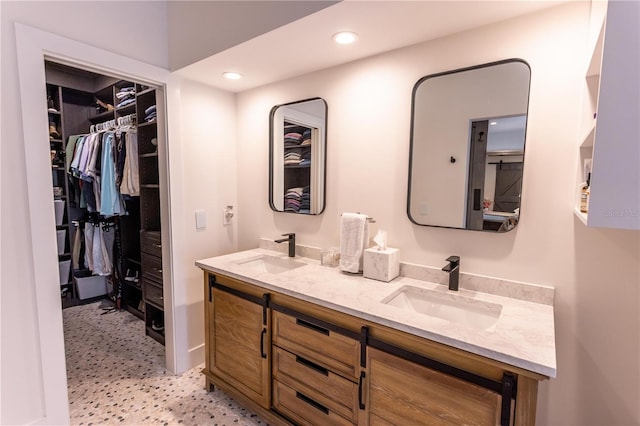 full bath featuring double vanity, recessed lighting, a walk in closet, and a sink