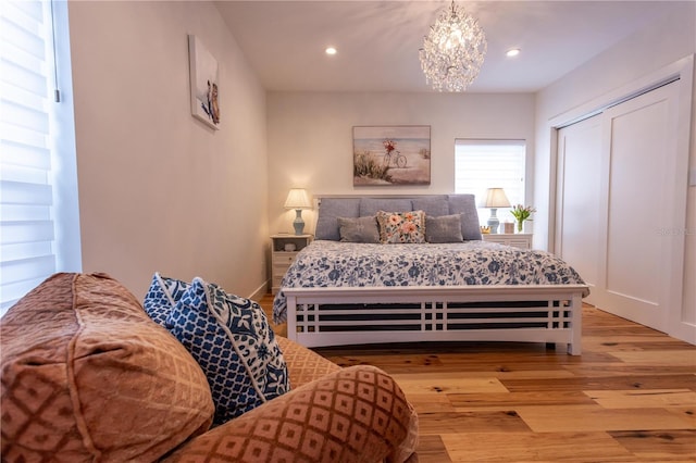 bedroom with light wood finished floors, a chandelier, recessed lighting, and a closet