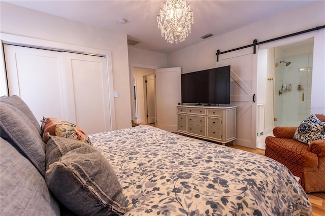 bedroom featuring visible vents, a closet, ensuite bathroom, a barn door, and a chandelier