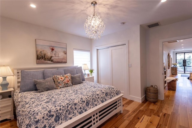 bedroom with visible vents, recessed lighting, an inviting chandelier, wood finished floors, and a closet