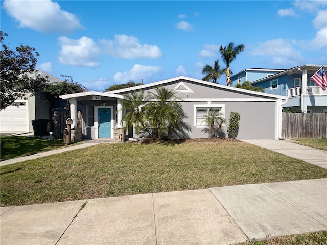 view of front of property with stucco siding, fence, concrete driveway, and a front yard