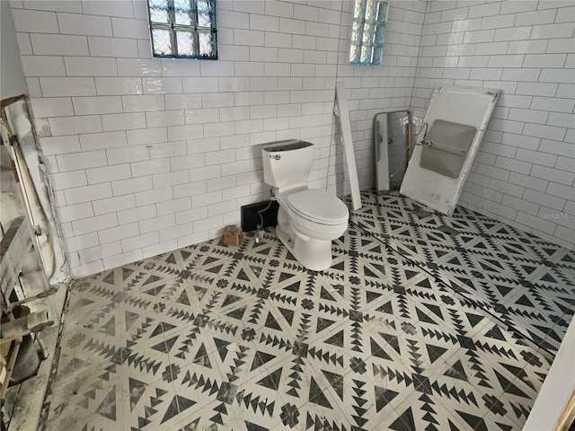 bathroom with toilet, tile walls, and tile patterned floors