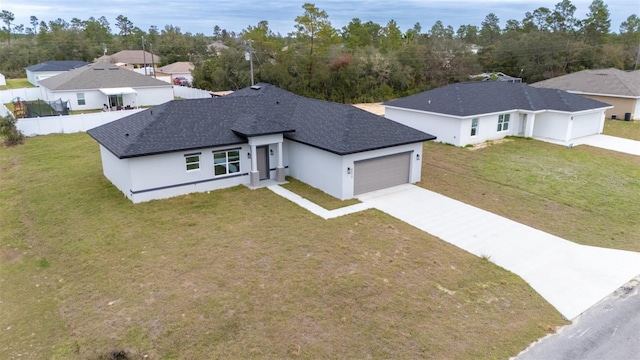 view of front facade featuring a shingled roof, fence, a garage, driveway, and a front lawn