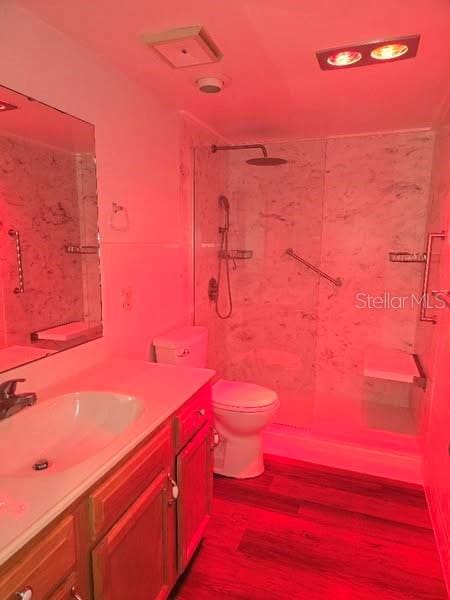 full bathroom featuring wood finished floors, vanity, toilet, and a walk in shower