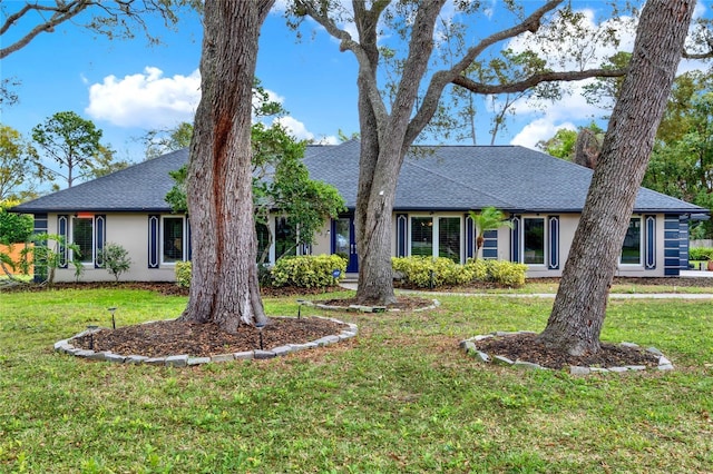 single story home with a shingled roof, a front yard, and stucco siding