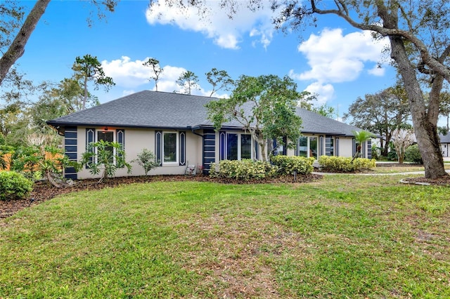 ranch-style house featuring stucco siding, a front yard, and a shingled roof