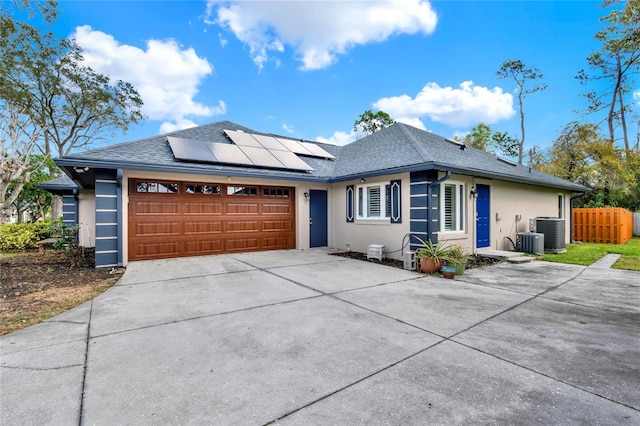 view of front of home featuring solar panels, roof with shingles, stucco siding, a garage, and driveway