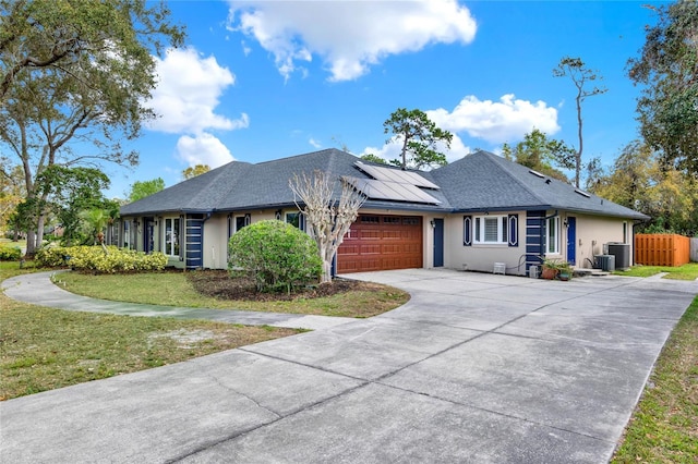 ranch-style house with fence, solar panels, stucco siding, a garage, and central air condition unit