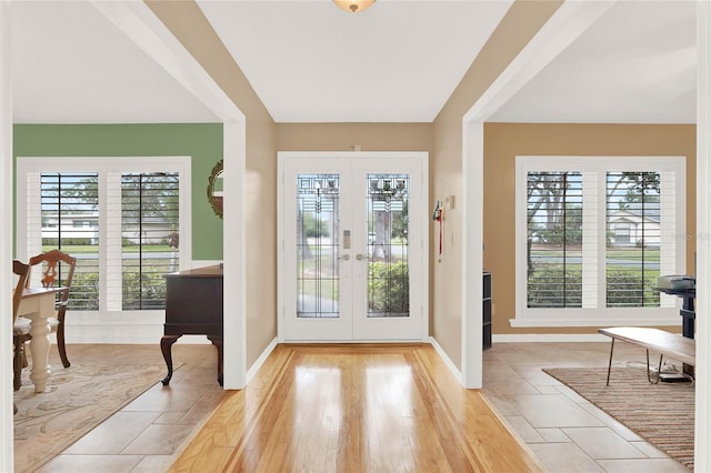 foyer entrance with plenty of natural light, french doors, baseboards, and light wood finished floors