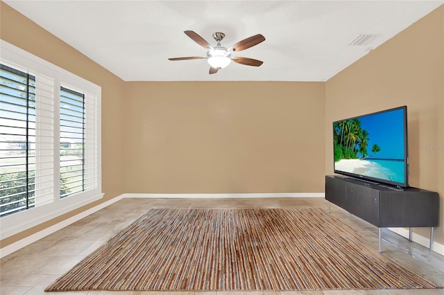 tiled empty room featuring visible vents, baseboards, and ceiling fan