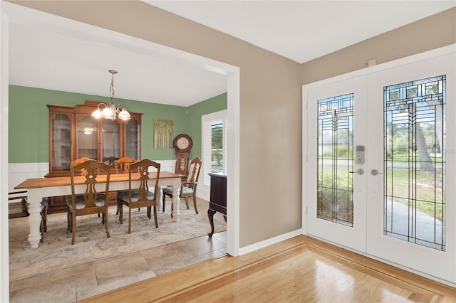 dining space featuring light wood-type flooring, french doors, and an inviting chandelier