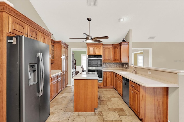 kitchen featuring a kitchen island, stone tile flooring, a sink, appliances with stainless steel finishes, and backsplash