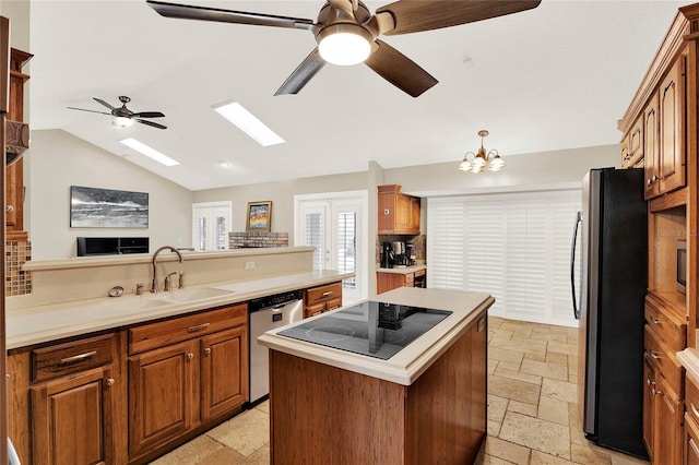 kitchen with a sink, appliances with stainless steel finishes, stone tile flooring, and light countertops