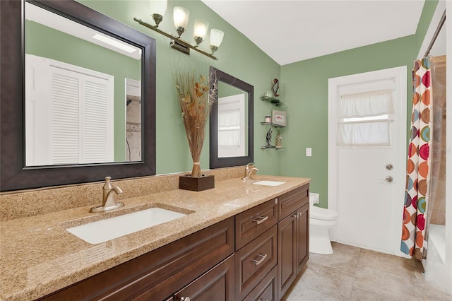 bathroom with a shower with curtain, double vanity, toilet, and a sink