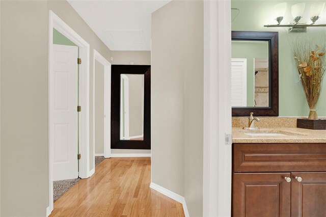 hallway with a sink, baseboards, and light wood-style floors