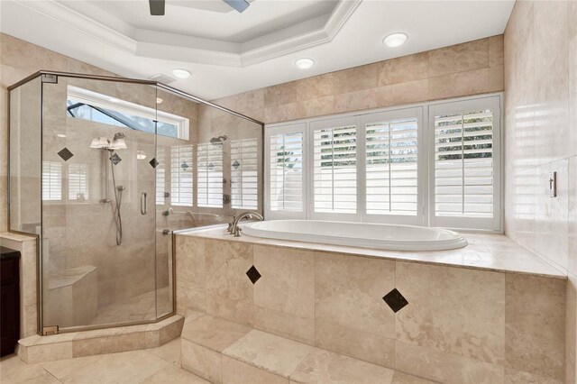 bathroom featuring a garden tub, a ceiling fan, a stall shower, and a tray ceiling