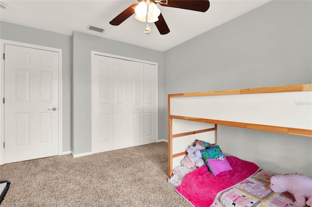 carpeted bedroom featuring a closet, visible vents, baseboards, and ceiling fan