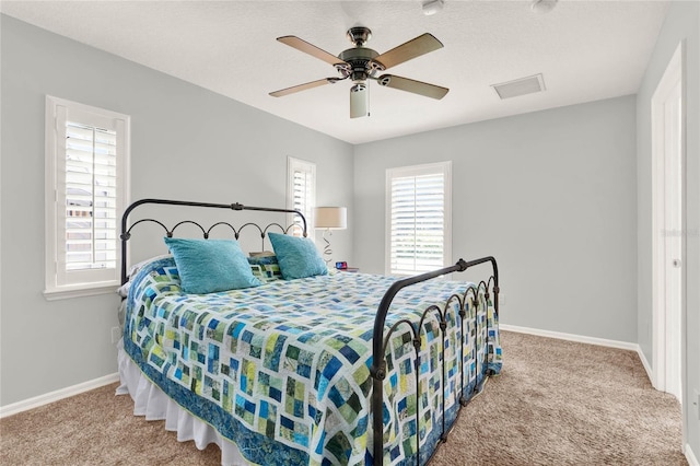 carpeted bedroom with baseboards, multiple windows, a textured ceiling, and a ceiling fan