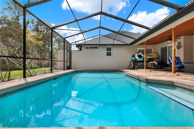 pool featuring glass enclosure, a patio area, and ceiling fan