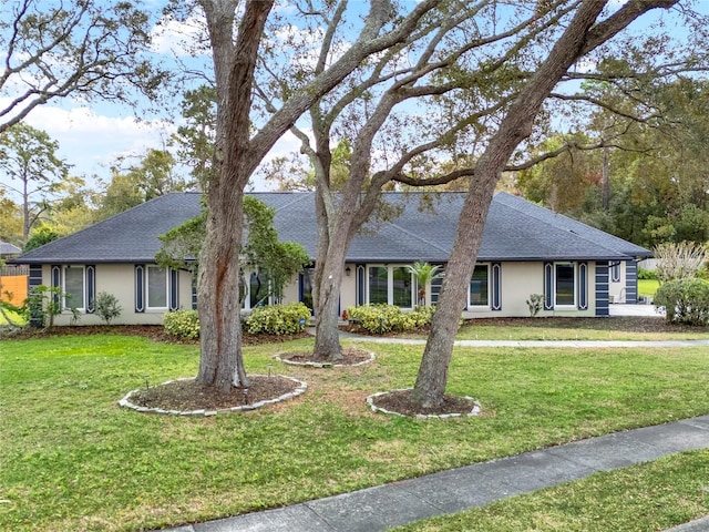 single story home with stucco siding, a shingled roof, and a front yard