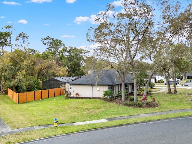 view of side of property featuring a yard, a shingled roof, and fence